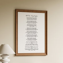 Load image into Gallery viewer, Framed poem on a wall above a wooden shelf with books and a lamp.