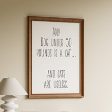 Load image into Gallery viewer, Any dog under 50 pounds is a cat and cats are useless, in tall black minimalist lettering on a white background in a wooden frame