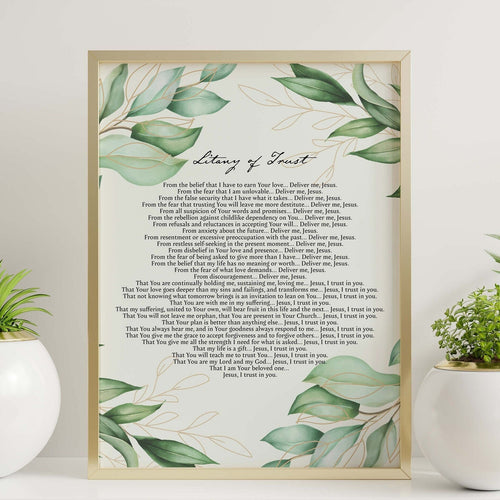May include: A framed print with a gold frame and a white background. The print features a watercolor illustration of green leaves and gold lines. The text on the print reads 'Litany of Trust' and includes a prayer asking for deliverance from fear and a list of things to trust in God for. The print is sitting on a shelf with two potted plants, one with a white pot and the other with a white pot with a gold rim.