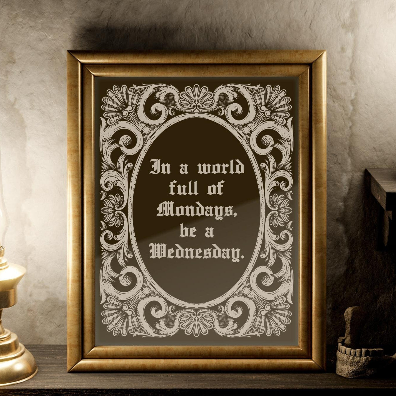 May include: A gold framed mirror with a decorative border. The mirror reflects a candle and a lamp. The mirror has a quote inside: 'In a world full of Mondays, be a Wednesday.'