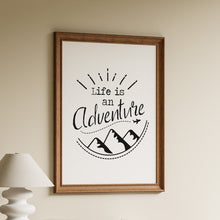 Load image into Gallery viewer, Life is an Adventure in black hand-lettered script with a sunburst, mountain peaks and a small airplane on a dotted flight path

