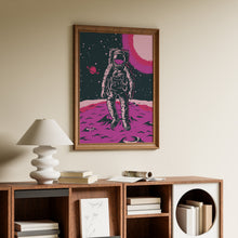 Load image into Gallery viewer, Retro astronaut standing on a pink magenta cratered planet with a ringed planet and glowing pink sun in a starry sky, in a wooden frame
